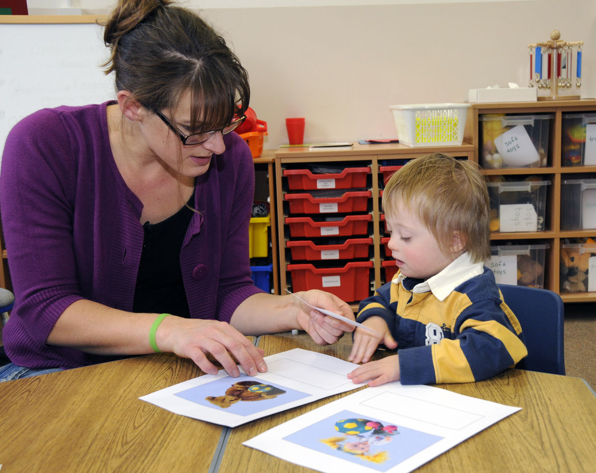 Photograph of a child with Down syndrome learning early vocabulary by selecting pictures.