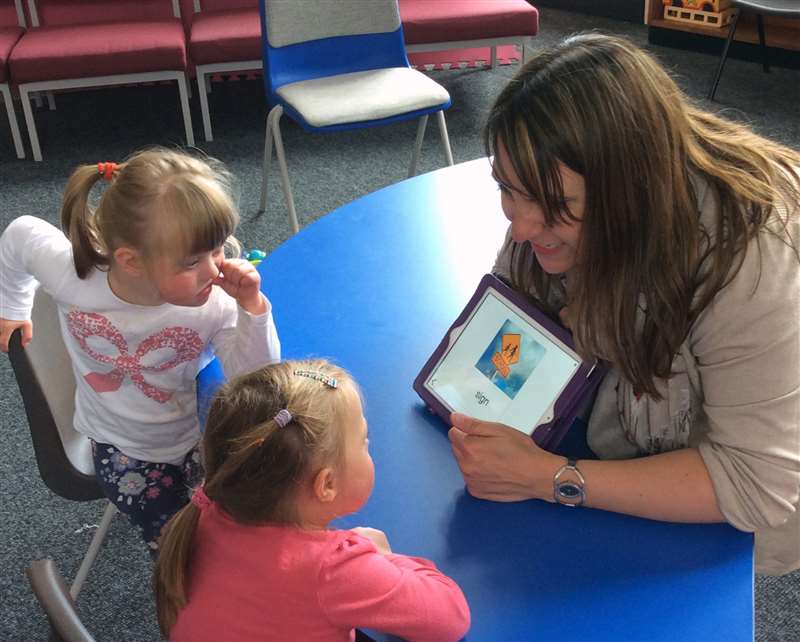 A photograph of a speech pathologist working with children with Down syndrome